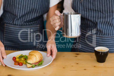 Mid section of two waitresses holding plate of meal and coffee j