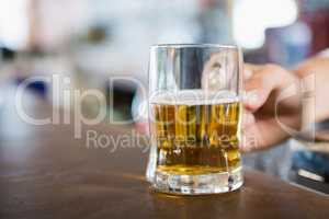 Close-up of man holding beer mug on the counter