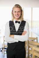 Waiter with arms crossed standing in restaurant