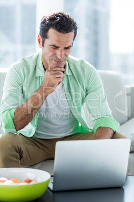 Concentrated man using laptop at home