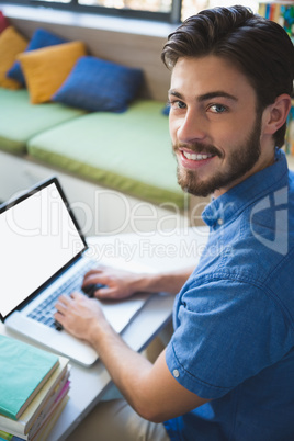 School teacher working on laptop in library