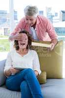 Smiling man surprising woman while holding gift