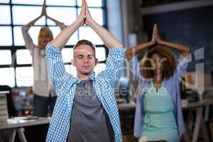 Businessman practicing yoga with coworkers