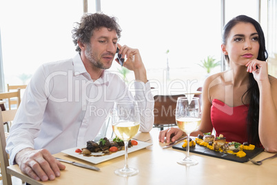 Woman sitting while man talking on mobile phone