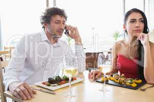 Woman sitting while man talking on mobile phone