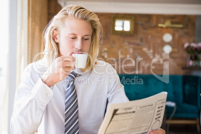 Man having coffee while reading newspaper