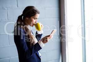 Woman drinking coffee while using phone