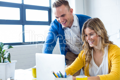 Joyful colleagues using laptop in office