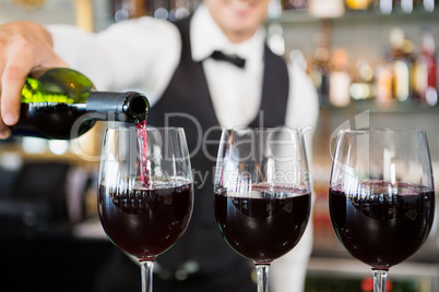 Waiter pouring wine into glasses