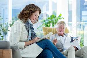 Mature woman by man using digital tablet