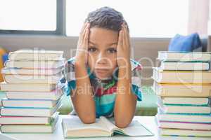 Schoolboy reading a book in library