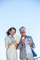 Smiling couple using digital tablet and mobile phon