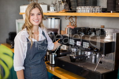 Portrait of smiling waitress making cup of coffee