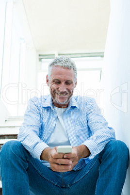 Smiling mature man using smartphone at home