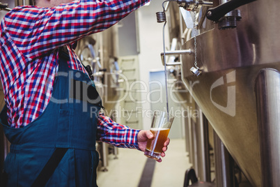 Manufacturer filling beer from storage tank