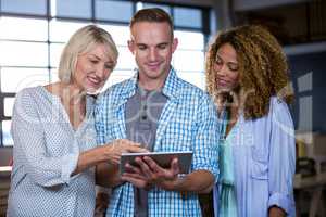 Smiling business people discussing over digital tablet