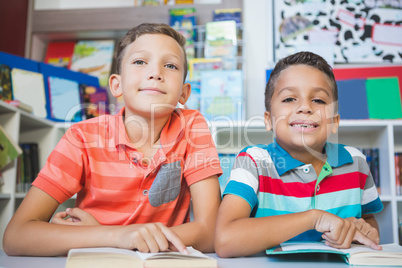 Schoolkids reading book in library