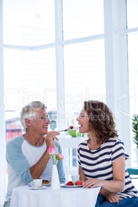 Smiling man feeding food to woman