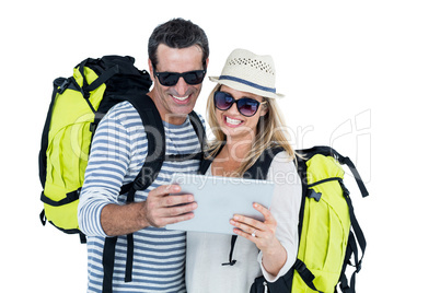 Couple with luggage looking in digital tablet