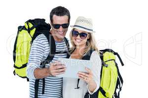 Couple with luggage looking in digital tablet