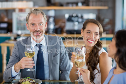 Businessman smiling at camera while colleague toasting glasses o