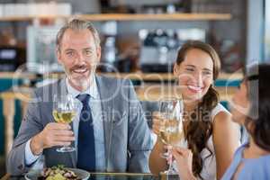 Businessman smiling at camera while colleague toasting glasses o