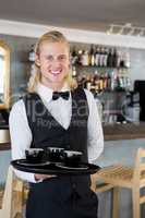 Waiter holding a tray with coffee cups in restaurant