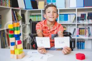 Disabled boy showing placard that reads I Can in library