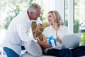 Happy man giving gift to woman with laptop