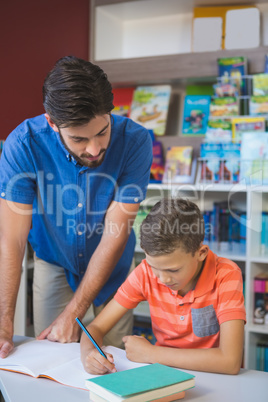 Teacher helping school kid with his homework in library