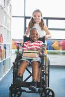 Happy schoolgirl carrying schoolboy in wheelchair