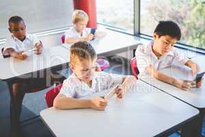 Schoolkids using mobile phone in classroom