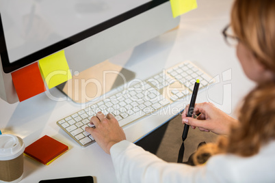 Businesswoman working with graphics tablet at desk