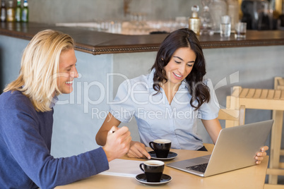 Business colleagues using laptop while having a cup of tea