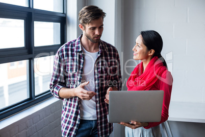 Colleagues discussing with laptop in office