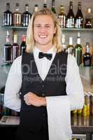 Portrait of waiter standing at bar counter