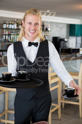 Waiter holding a tray with coffee cups in restaurant