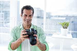 Man holding camera while sitting at home