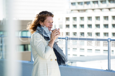 Woman drinking coffee by railing Woman drinking coffee by railing