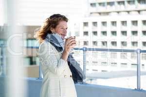 Woman drinking coffee by railing
