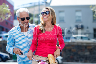 Mature couple riding bicycle on city street