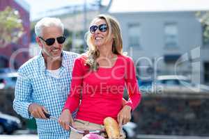 Mature couple riding bicycle on city street