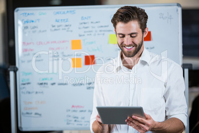 Businessman using digital tablet against whiteboard