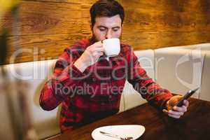 Man using mobile phone while having coffee in restaurant