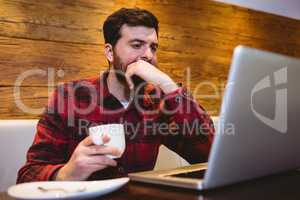 Man using laptop at table in restaurant