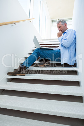 Concentrated man using laptop on steps Concentrated man using laptop on steps