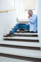 Concentrated man using laptop on steps