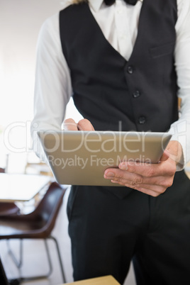 Waiter using digital tablet in restaurant