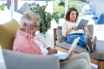 Woman using digital tablet while relaxing on seat