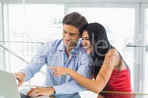 Happy couple using laptop in cafe